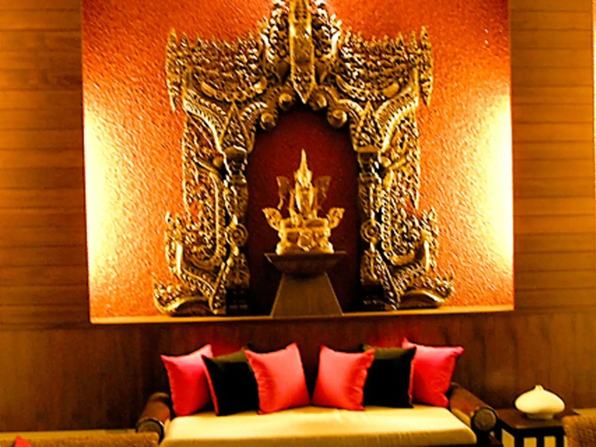 Traditional golden Thai shrine with carved woodwork and decorative red cushions